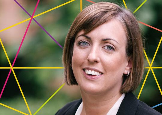 Image of Vicci smiling at the camera, she has short dark hair and is wearing a white top and dark jacket.