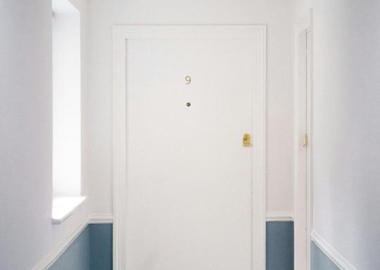 Image of the white door of a flat with a doormat outside
