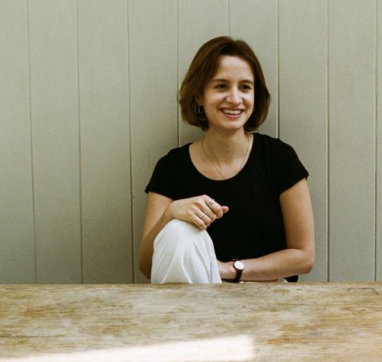 Image of Celestine, who is sitting at a table, smiling